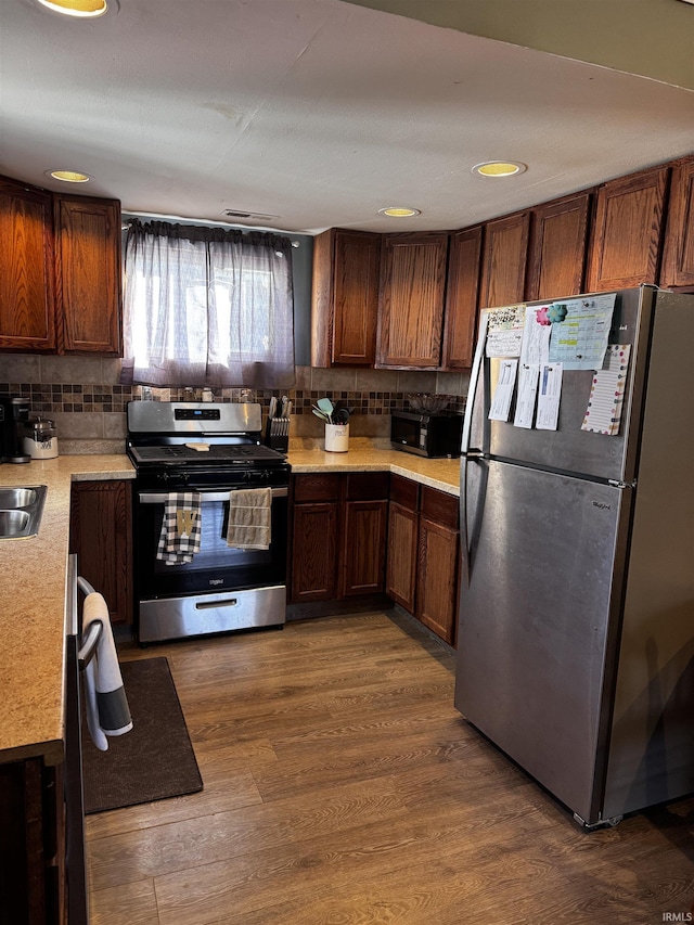 kitchen featuring appliances with stainless steel finishes, dark hardwood / wood-style floors, sink, and decorative backsplash