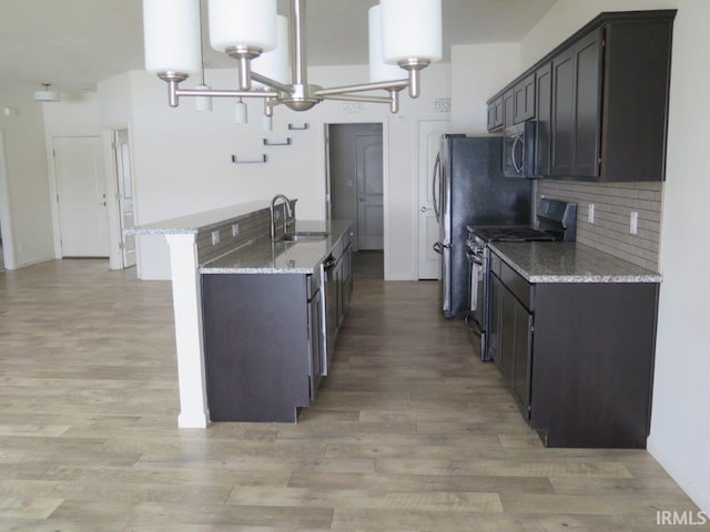 kitchen with sink, light stone counters, dark brown cabinets, light wood-type flooring, and range with gas stovetop