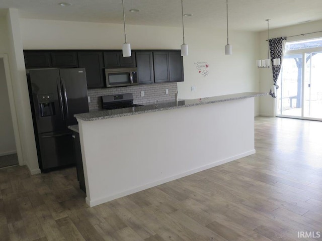 kitchen with tasteful backsplash, decorative light fixtures, light stone countertops, and appliances with stainless steel finishes