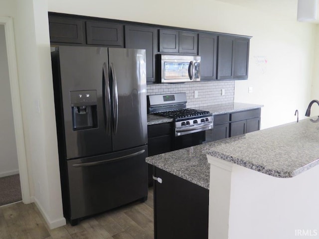 kitchen with a kitchen island, appliances with stainless steel finishes, dark hardwood / wood-style flooring, and decorative backsplash