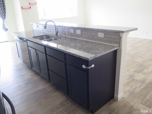 kitchen featuring tasteful backsplash, dishwasher, sink, light stone counters, and dark wood-type flooring