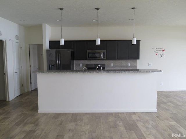 kitchen with light hardwood / wood-style flooring, pendant lighting, stainless steel appliances, light stone countertops, and decorative backsplash