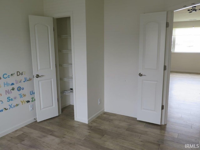 unfurnished bedroom featuring a walk in closet, light wood-type flooring, and a closet