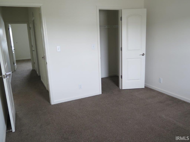 unfurnished bedroom with a closet and dark colored carpet