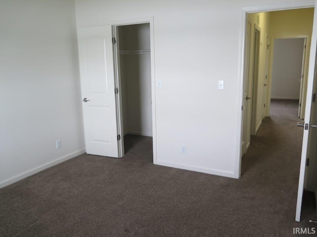 unfurnished bedroom featuring dark carpet and a closet