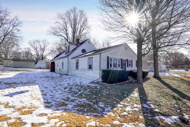 view of snow covered exterior with an outbuilding and a garage