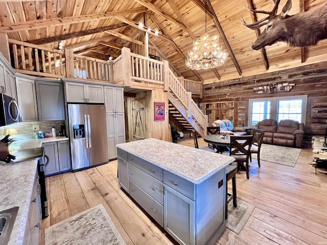 kitchen with beam ceiling, gray cabinets, stainless steel appliances, and a center island