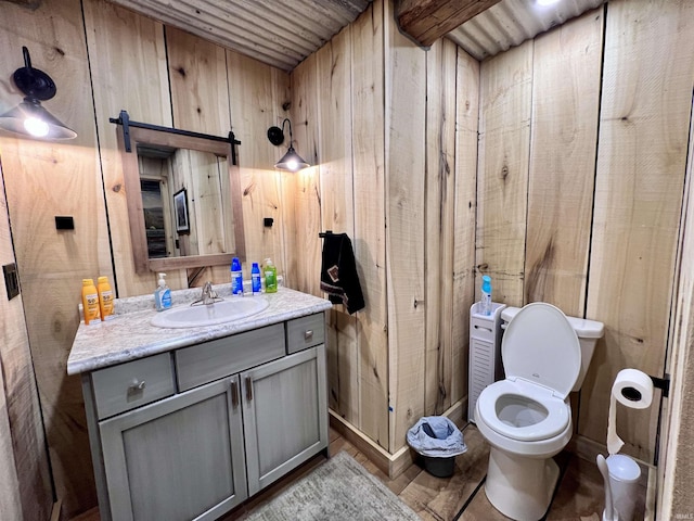 bathroom featuring wooden walls, vanity, toilet, and hardwood / wood-style floors