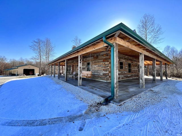 view of snow covered exterior with a garage and an outdoor structure