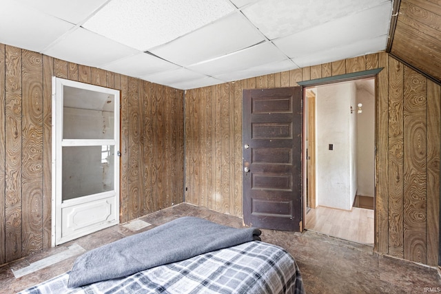 bedroom featuring a paneled ceiling and wooden walls