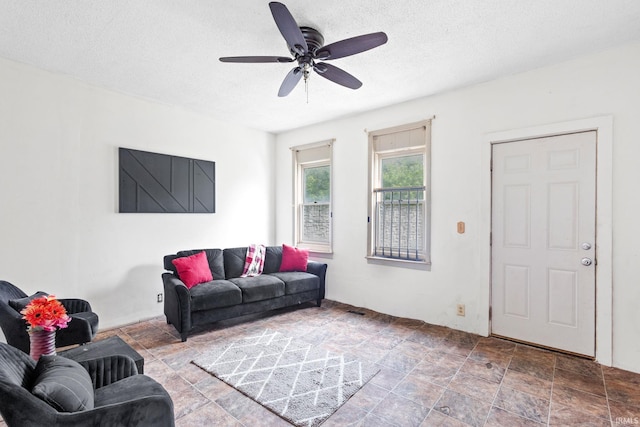 living room featuring ceiling fan and a textured ceiling