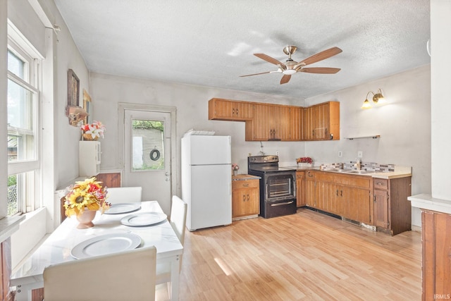 kitchen with black / electric stove, sink, white fridge, a textured ceiling, and light hardwood / wood-style flooring