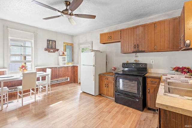 kitchen featuring light wood-type flooring, a textured ceiling, white fridge, and electric range