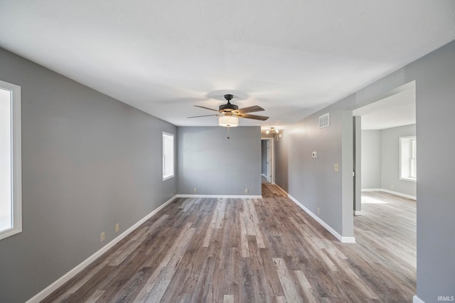 spare room featuring wood-type flooring, a healthy amount of sunlight, and ceiling fan