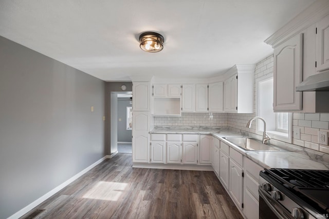 kitchen featuring dark wood-type flooring, stainless steel gas range, sink, white cabinetry, and tasteful backsplash