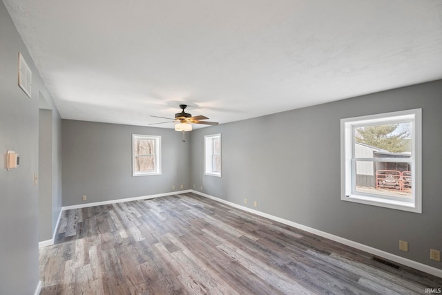 unfurnished room with hardwood / wood-style flooring, a healthy amount of sunlight, and ceiling fan