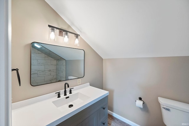 bathroom with lofted ceiling, toilet, hardwood / wood-style floors, and vanity