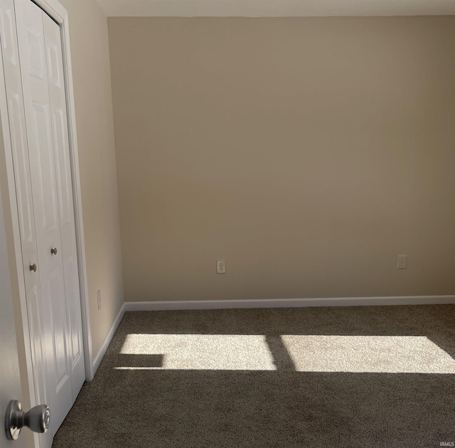 unfurnished bedroom featuring dark carpet and a closet