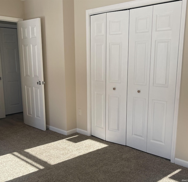 unfurnished bedroom featuring a closet and dark colored carpet