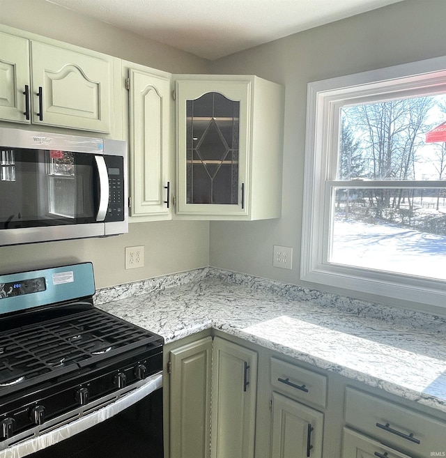 kitchen with light stone countertops, stainless steel appliances, and white cabinets