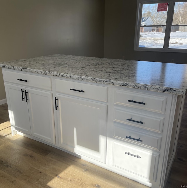 kitchen featuring white cabinetry, light stone countertops, and light wood-type flooring