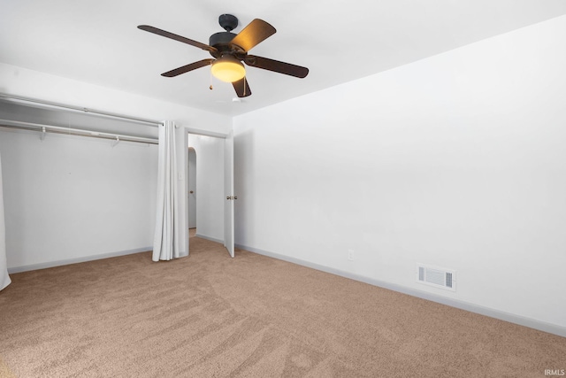 unfurnished bedroom featuring light colored carpet, ceiling fan, and a closet