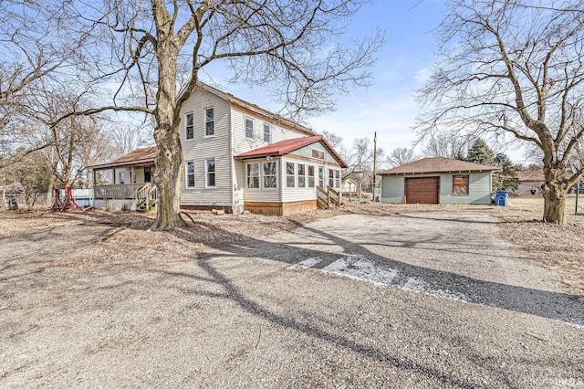 view of side of property featuring an outbuilding, a garage, and a porch