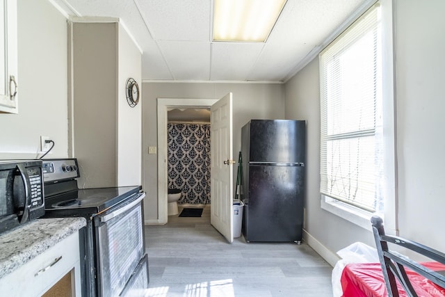 kitchen with white cabinetry, light hardwood / wood-style flooring, light stone counters, and black appliances