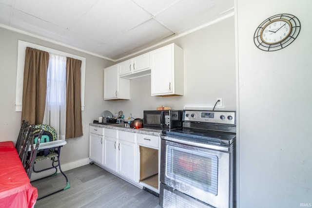 kitchen with a paneled ceiling, white cabinets, light wood-type flooring, and stainless steel electric range