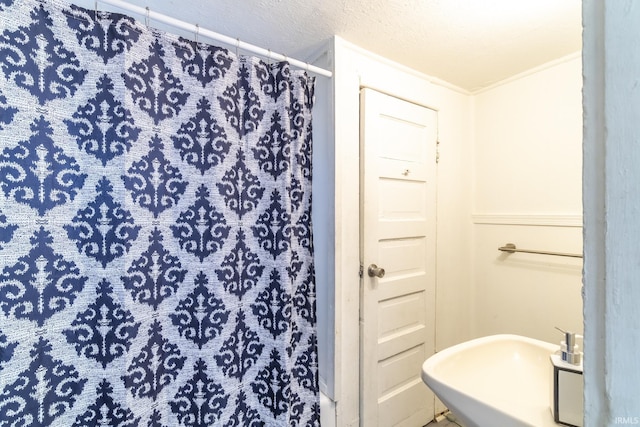 bathroom with crown molding, a shower with curtain, sink, and a textured ceiling