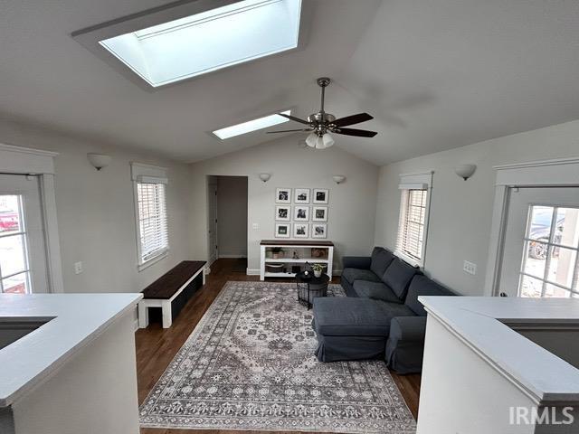 living room with dark wood-type flooring, plenty of natural light, and lofted ceiling with skylight