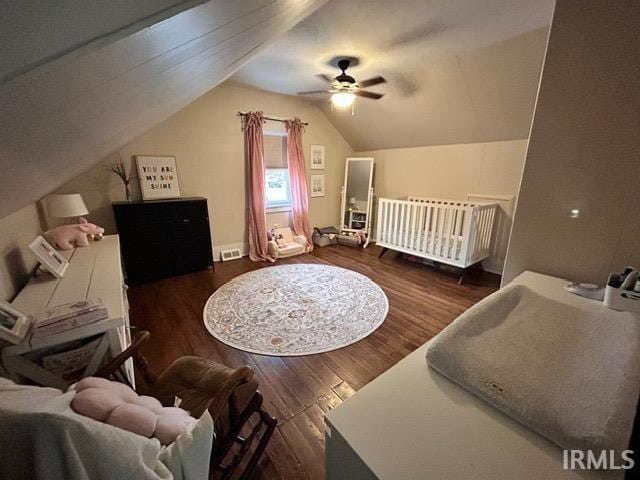 bedroom with ceiling fan, dark hardwood / wood-style flooring, vaulted ceiling, and a crib