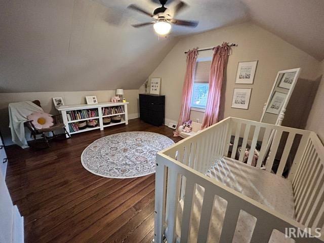 bedroom featuring dark hardwood / wood-style flooring, lofted ceiling, a nursery area, and ceiling fan