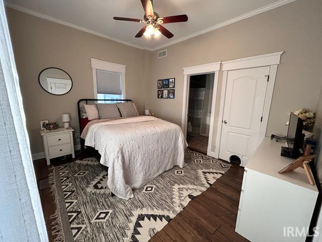 bedroom with ceiling fan, ornamental molding, and dark hardwood / wood-style flooring