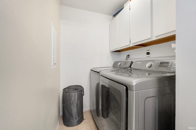 laundry room with cabinets, washing machine and dryer, and light tile patterned floors