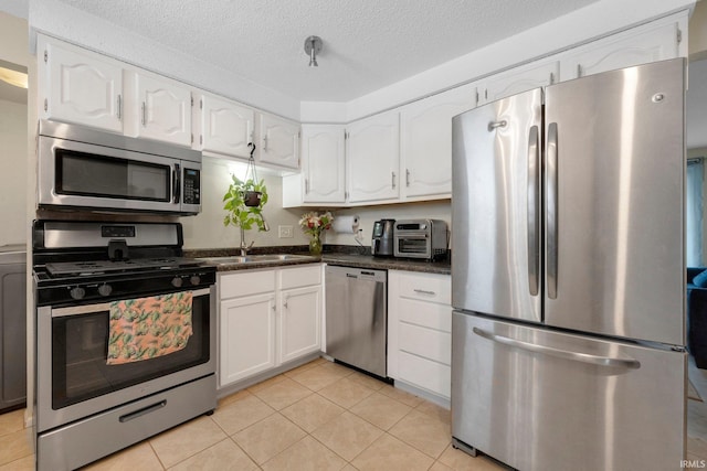 kitchen featuring sink, a textured ceiling, light tile patterned floors, stainless steel appliances, and white cabinets