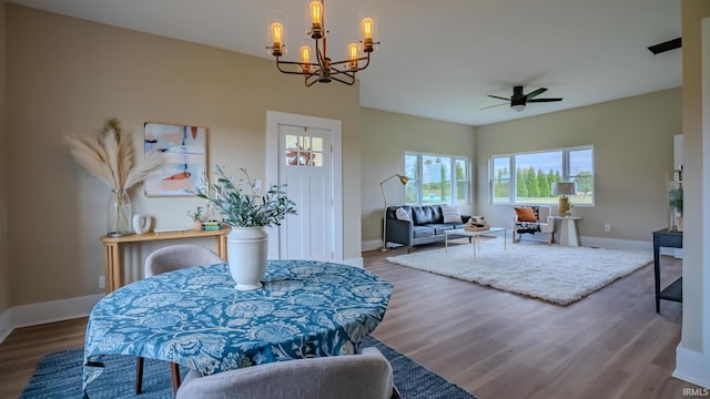 dining area featuring wood-type flooring and ceiling fan with notable chandelier