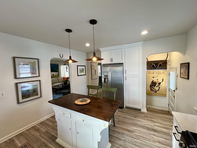 kitchen featuring white cabinetry, a center island, stainless steel fridge with ice dispenser, hanging light fixtures, and hardwood / wood-style floors