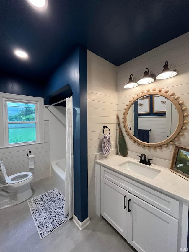 full bathroom featuring vanity, wooden walls, toilet, and washtub / shower combination