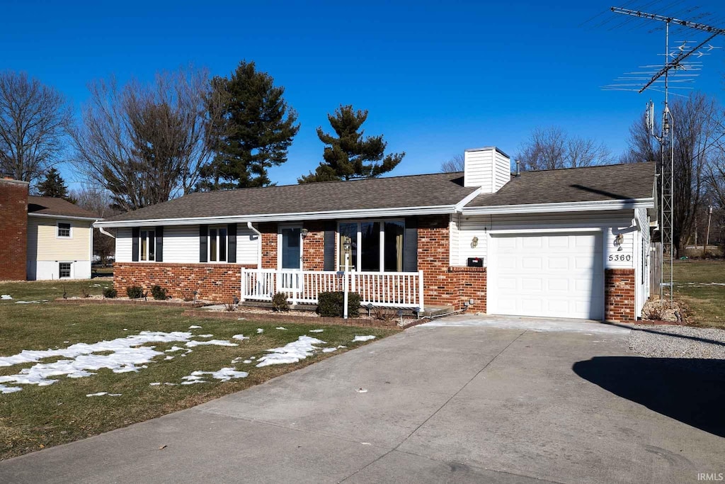 ranch-style house with a garage, covered porch, and a front lawn