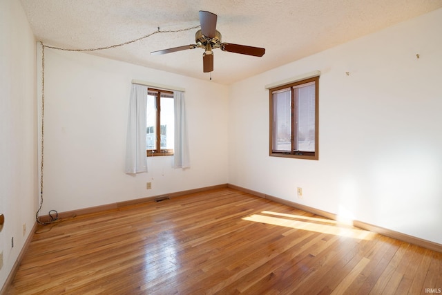 unfurnished room with ceiling fan, light hardwood / wood-style flooring, and a textured ceiling