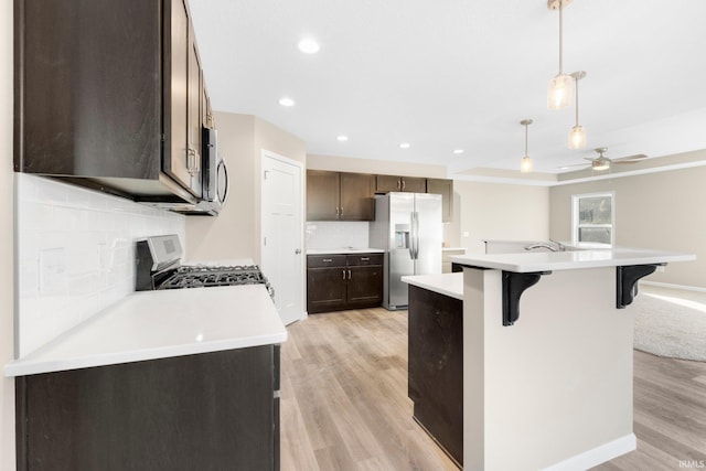 kitchen with a kitchen island with sink, hanging light fixtures, a kitchen breakfast bar, and appliances with stainless steel finishes