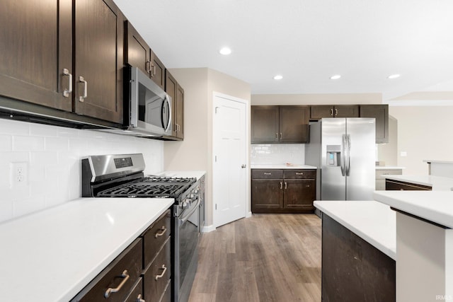 kitchen with dark brown cabinetry, appliances with stainless steel finishes, light hardwood / wood-style floors, and backsplash