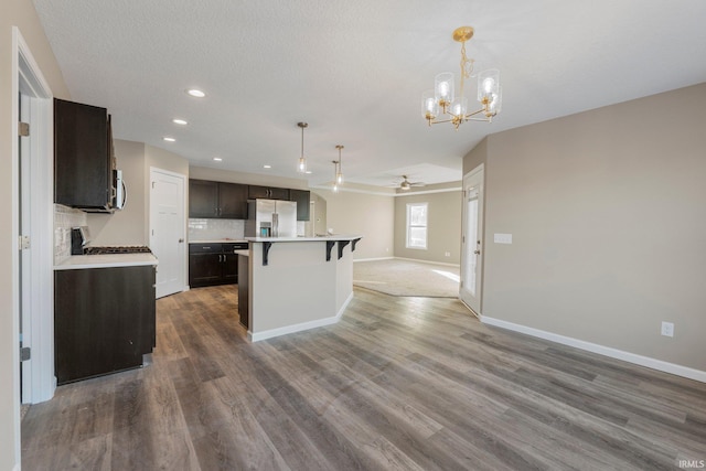 kitchen featuring stainless steel fridge, ceiling fan with notable chandelier, a kitchen island, decorative backsplash, and decorative light fixtures