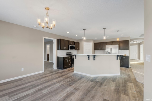 kitchen featuring appliances with stainless steel finishes, pendant lighting, a breakfast bar area, and decorative backsplash