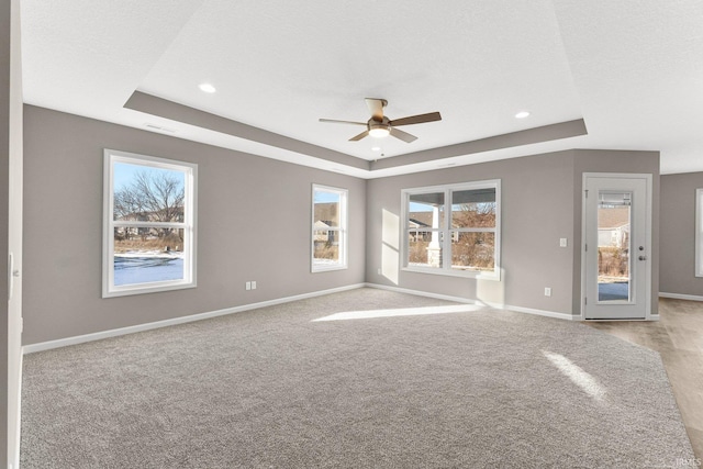 carpeted empty room with ceiling fan, a raised ceiling, and a textured ceiling