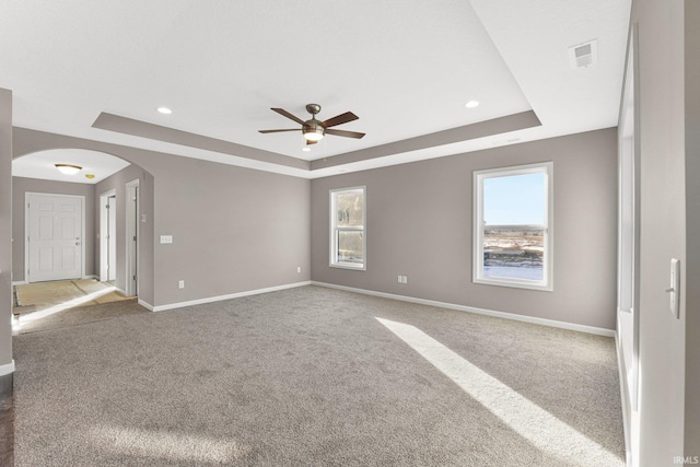 carpeted empty room with ceiling fan and a tray ceiling