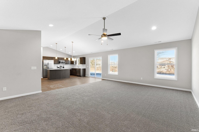 unfurnished living room with vaulted ceiling, carpet, a healthy amount of sunlight, and ceiling fan