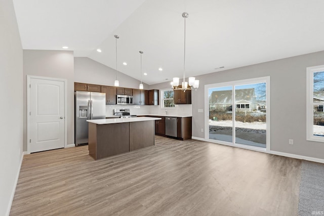 kitchen featuring an inviting chandelier, light hardwood / wood-style flooring, a kitchen island, pendant lighting, and stainless steel appliances