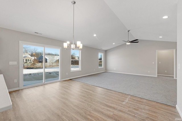 interior space featuring lofted ceiling, a healthy amount of sunlight, ceiling fan with notable chandelier, and light hardwood / wood-style flooring